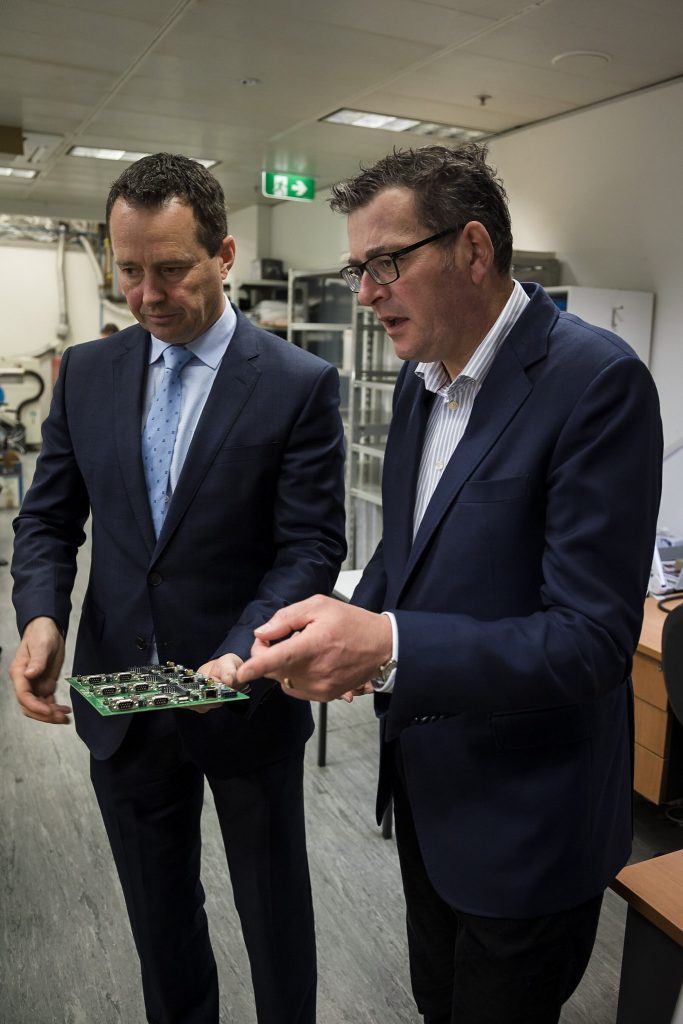 VIC Premier Dan Andrews holding an MTData tracking hardware component with MTData CEO Matthew Bellizia