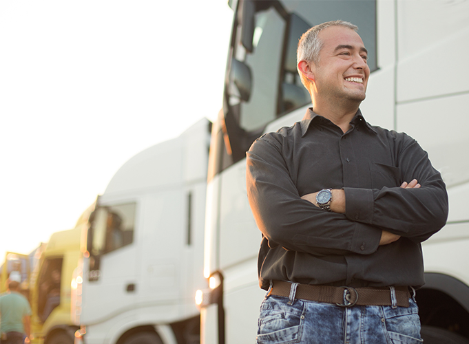 Man smiling standing in front of a fleet of white trucks